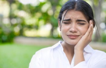 South Asian, Indian woman suffering from toothache, tooth decay, tooth sensitivity, wisdom tooth pain, cavity, dental care concept, outdoor background